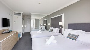Une chambre d’hôtel avec deux lits, un bureau doté d’un téléviseur à écran plat et un miroir.