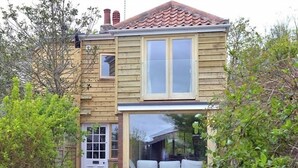 A two-story wooden house with a front porch, a small window, and a door.