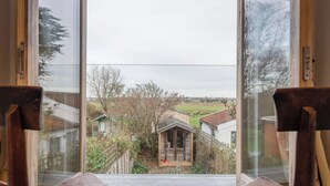 A room with a large window offering a view of a garden and neighboring houses.
