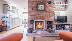 A cozy living room with a fireplace, a television, and a bookshelf.