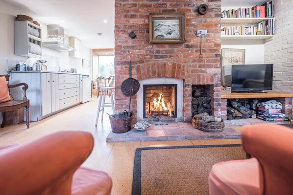 A cozy living room with a fireplace, a television, and a bookshelf.