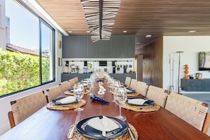 A long dining table set for a meal with a view of the outdoors.
