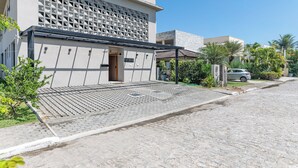 Un edificio moderno con facciata geometrica, ingresso coperto e vialetto lastricato.