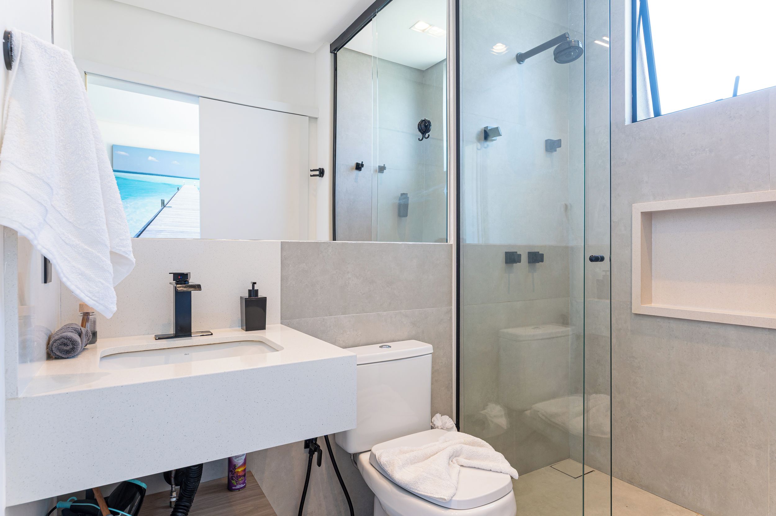 A modern bathroom with a glass shower enclosure, a white sink, and a toilet.