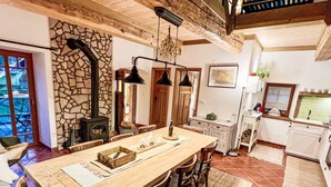 A spacious dining area with a long wooden table, stone wall, and a fireplace. - Vidochov by Interhome (Nova Paka)