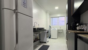 Une cuisine moderne avec des meubles blancs, un réfrigérateur en acier inoxydable et un plan de travail noir.