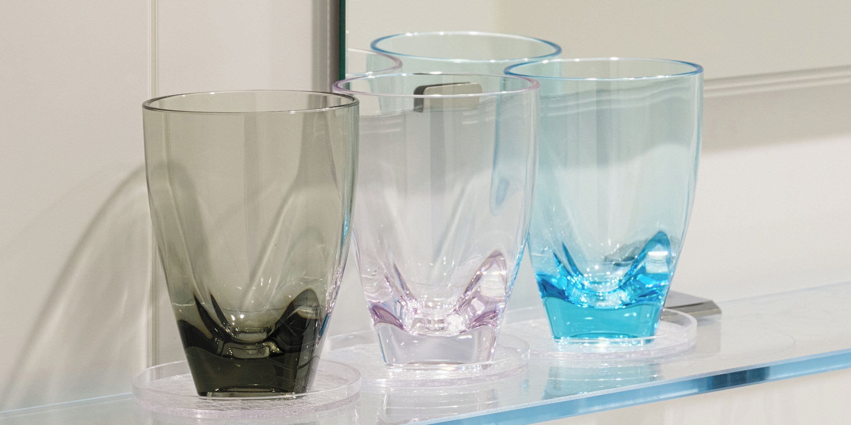 Trois vases en verre sont posés sur une étagère transparente.