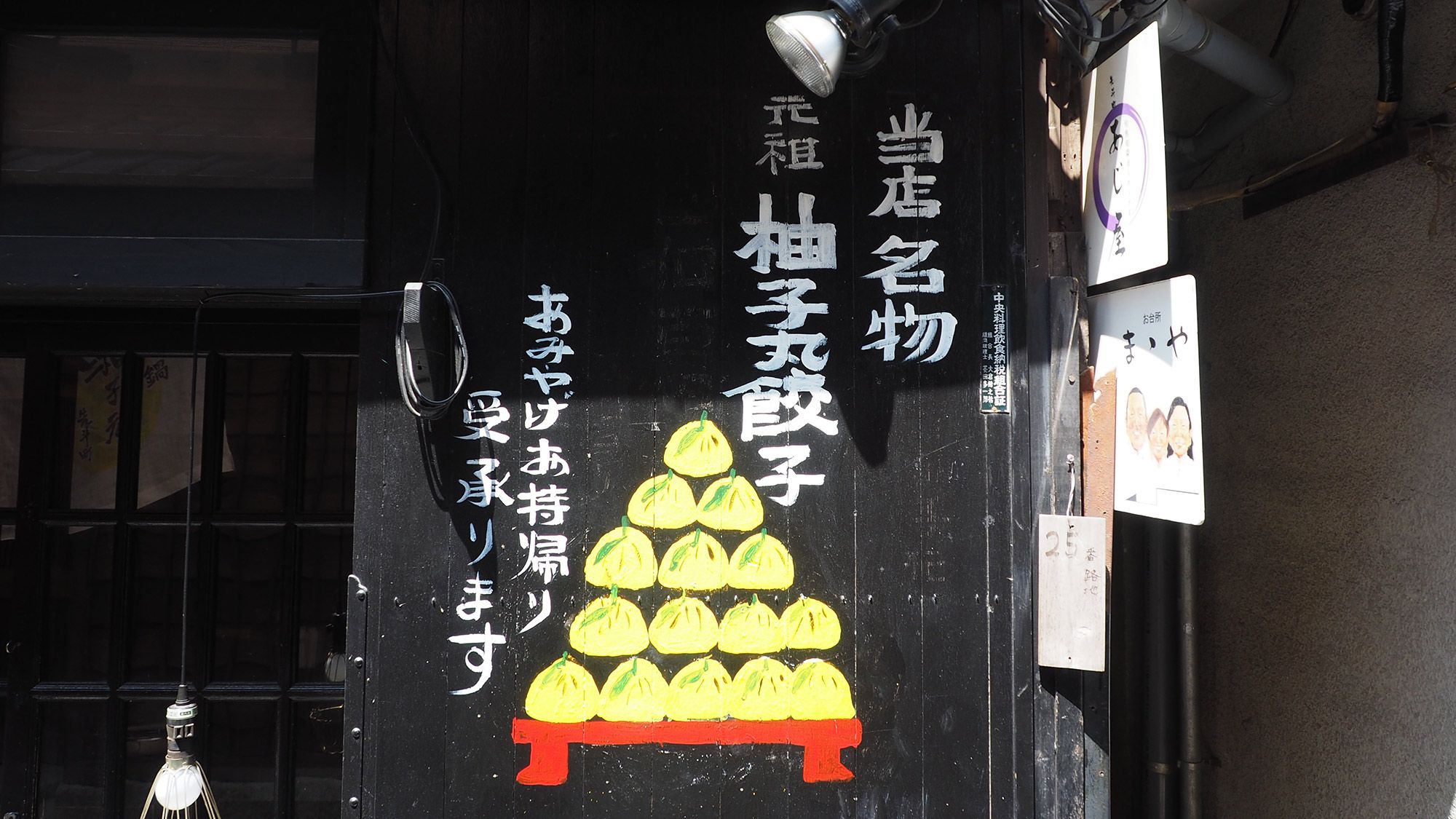A storefront with Japanese signage and a pyramid of yellow objects on a red stand.