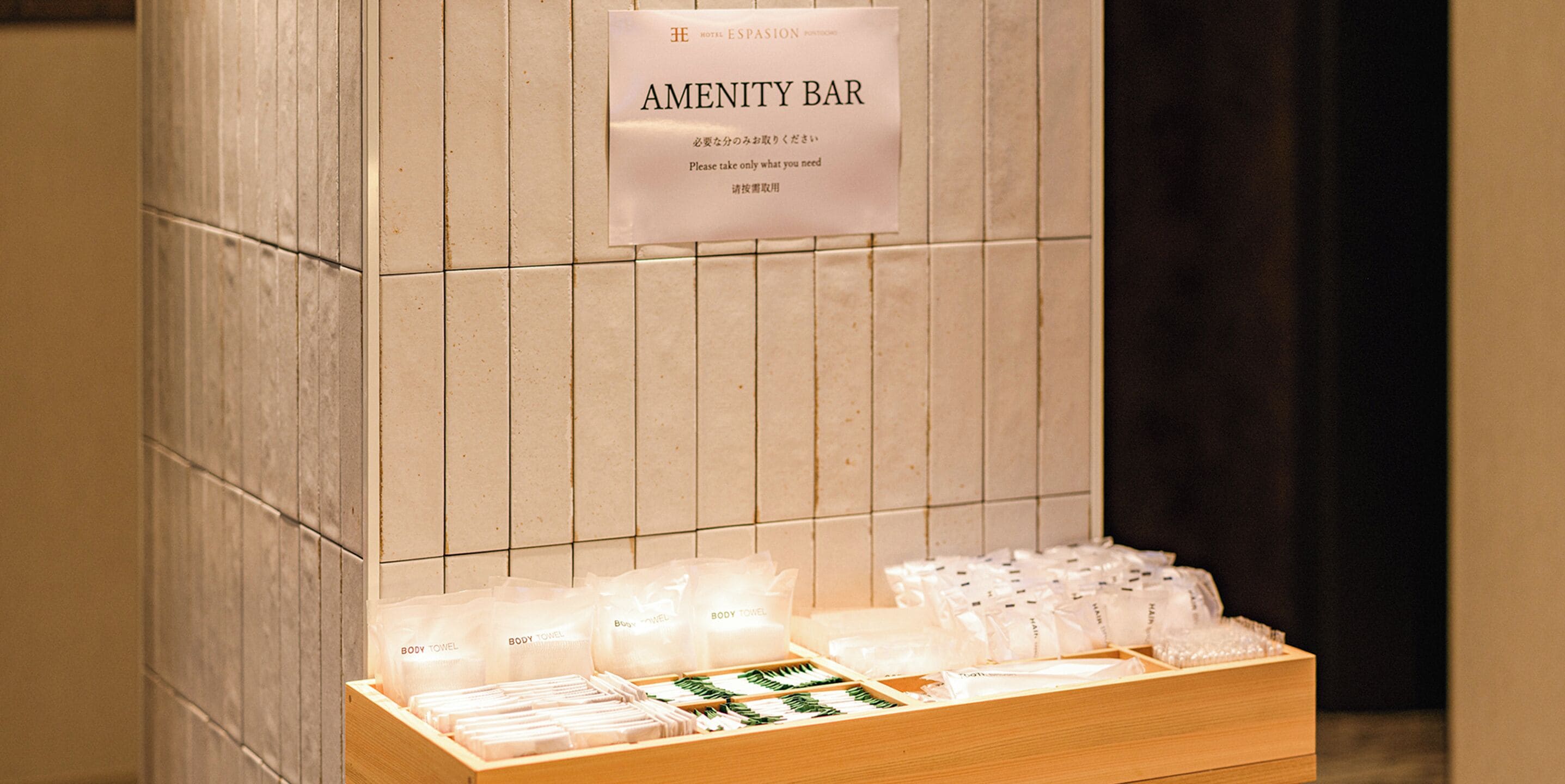 A wooden display with body towels and toiletries at a hotel amenity bar.
