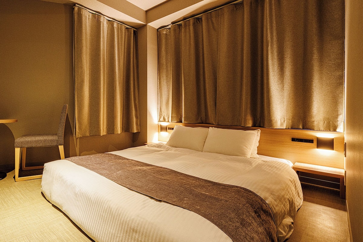 Una habitación de hotel con una cama grande, un escritorio y dos sillas.