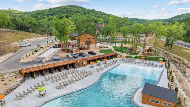 Een resort met een groot zwembad, buitenterras en uitzicht op de omliggende heuvels.