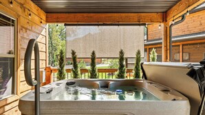 Een hottub in een houten chalet met uitzicht op bomen en een houten terras.