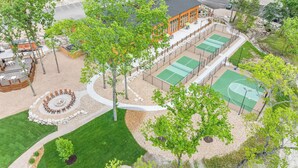 Luchtbeeld van een recreatiegebied met een tennisbaan, buitenzitplaatsen en een vuurkuil.