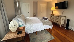 A bedroom with a bed, bedside tables, a lamp, a TV, and a wardrobe. - Mariam's On Becket (Salem)