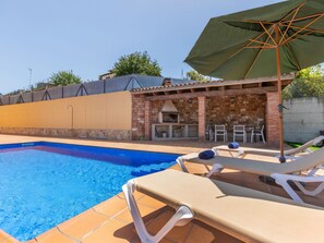 A swimming pool with lounge chairs and a barbecue area.