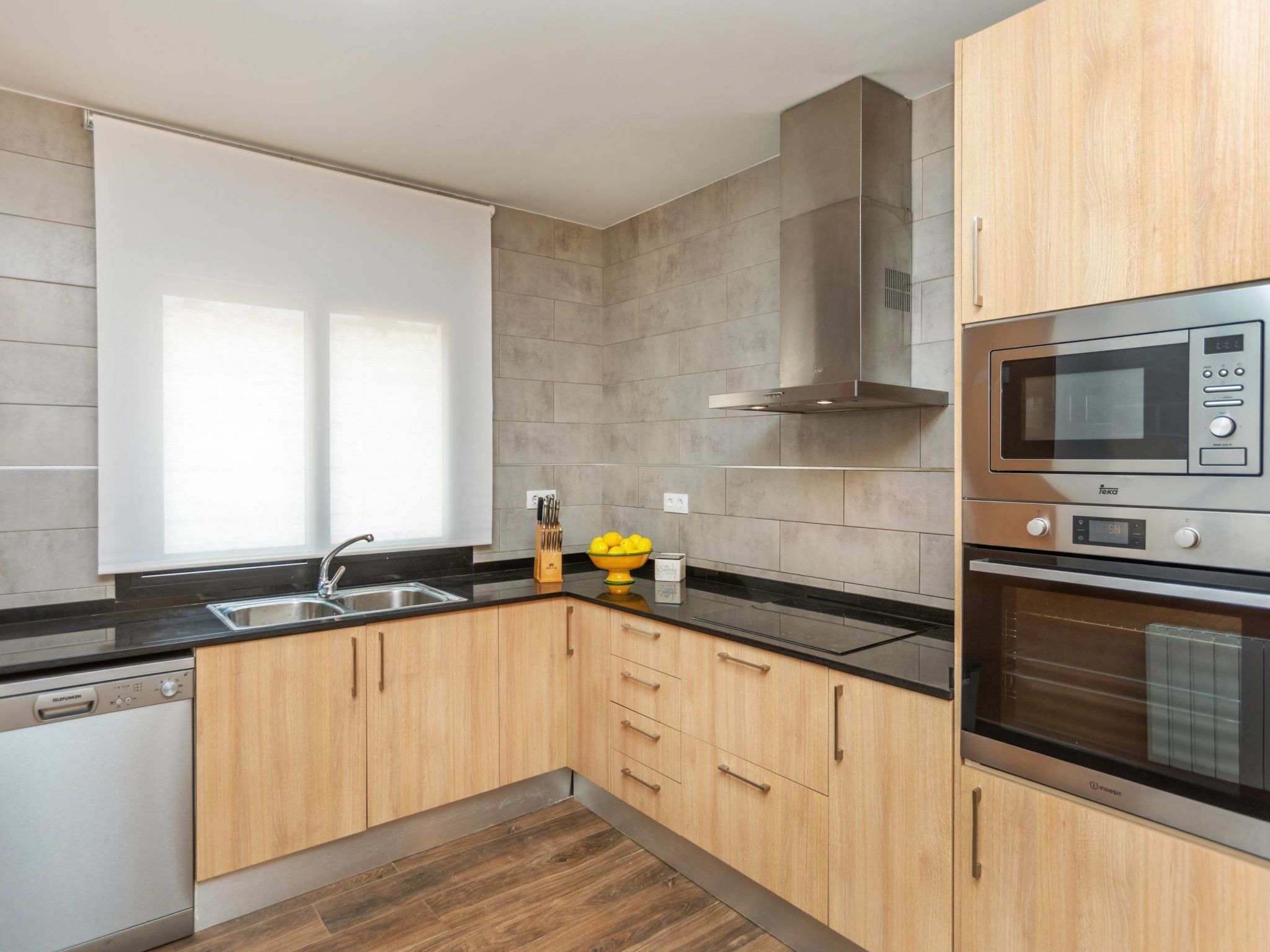 A modern kitchen with wooden cabinets, a stainless steel microwave, and an oven.
