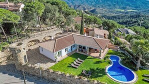 Eine Villa mit Swimmingpool, umgeben von üppiger Vegetation und Bergen.