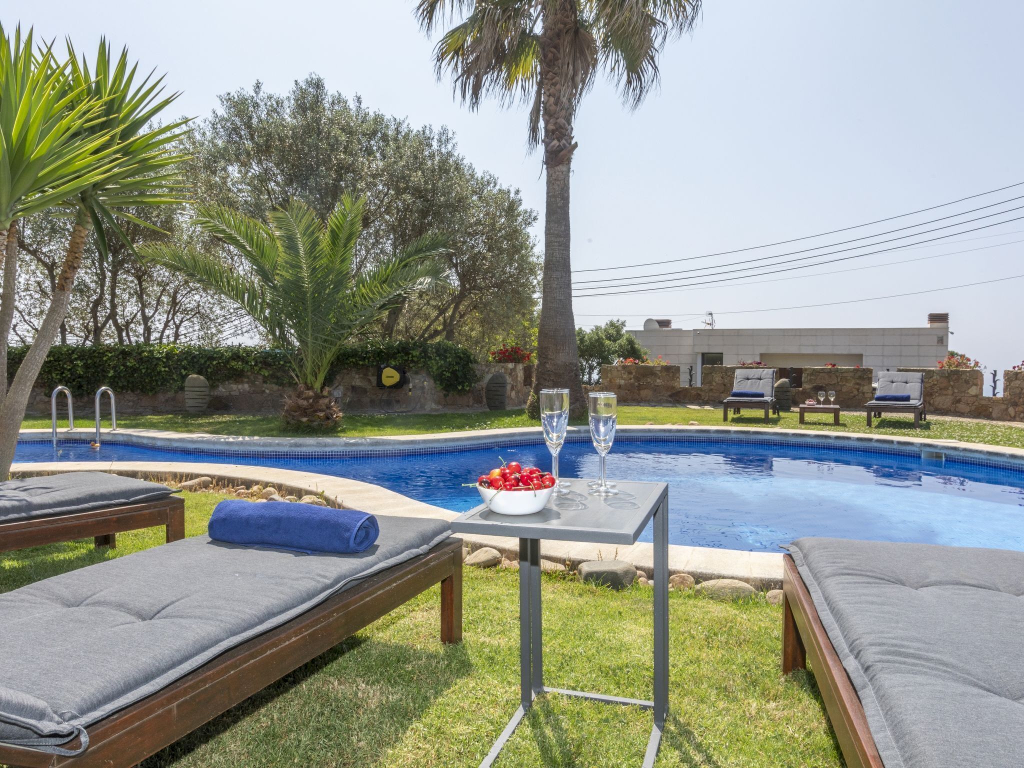 A poolside area with lounge chairs, a table with drinks, and a view of a building in the background.