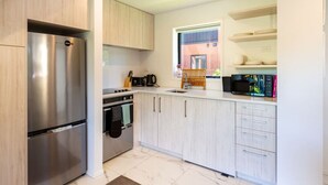 Una cocina moderna con electrodomésticos de acero inoxidable, armarios de madera clara y un ventanal con vistas al exterior.