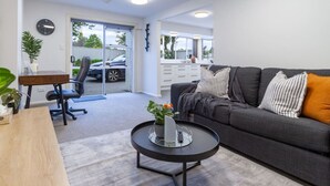 Ein modernes Wohnzimmer mit grauem Sofa, rundem Couchtisch und einem Essbereich mit Holztisch und Stühlen.