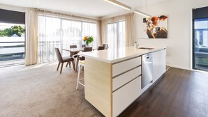 A modern kitchen with a large island, a dining area with chairs, and a large window with curtains.
