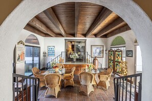 A dining area with wicker chairs, a glass table, and a wooden bench.