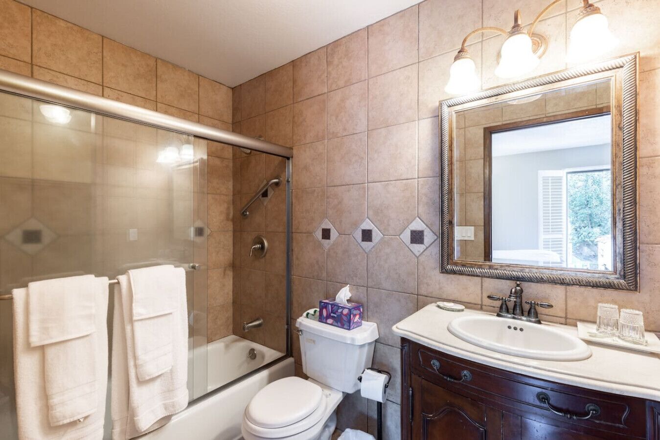 Ein Badezimmer mit Duschkabine, Toilette, Waschbecken und Waschtisch mit Spiegel.