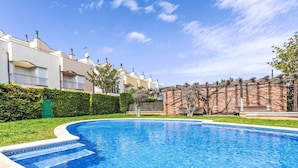 A swimming pool surrounded by a well-maintained garden and a row of residential buildings. - Bousquet by Interhome (L'Escala)