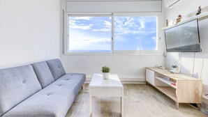 Ett modernt vardagsrum med en grå soffa, ett vitt soffbord och en tv som är monterad på väggen.