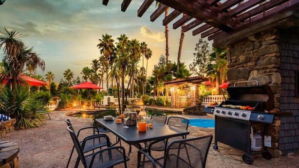An outdoor patio with a table set for dining, a grill, and a pool. - Villa Terra Bella, by Vinifera Homes (Windsor)