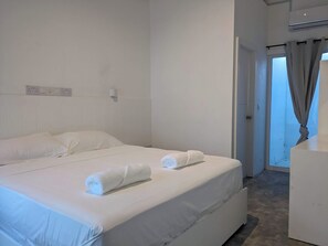 A hotel room with a large bed, a bedside table, and a view of the outside through a door. - Avi Guesthouse (Thoddoo)