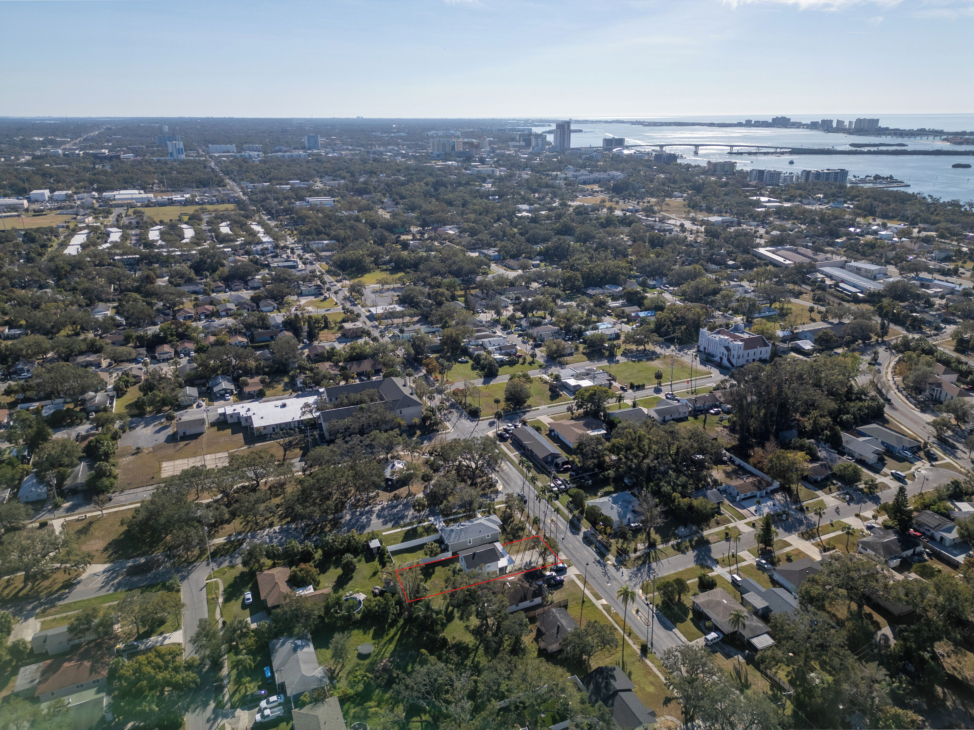 An aerial view of a residential area with houses, streets, and a bridge in the background.