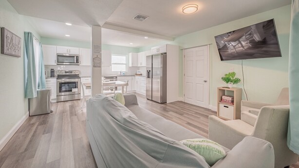 A modern living room with a sofa, a dining table, and a kitchen in the background.
