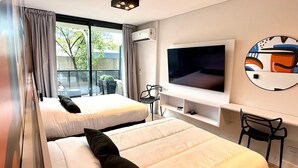 A modern hotel room with two beds, a large TV, and a balcony with outdoor seating. - CloudBA Godoy Cruz Soho Apartments (Buenos Aires)
