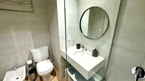 A modern bathroom with a toilet, bidet, sink, and mirror. - CloudBA Godoy Cruz Soho Apartments (Buenos Aires)