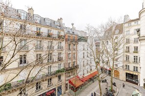 A multi-story building with balconies, a red awning, and a storefront with a sign. - Blueground | Le Marais, elev & w/d, nr Pompidou (Paris)