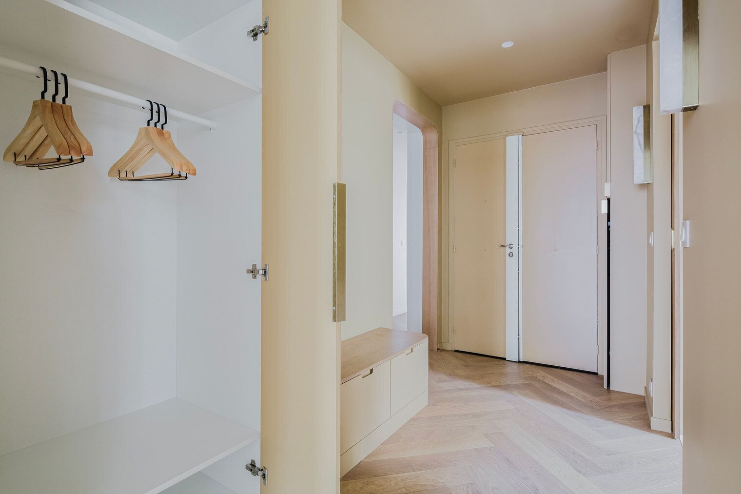 A hallway with wooden flooring, white walls, and a door at the end.