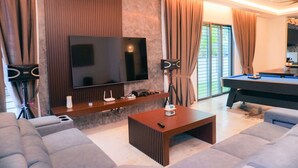 Een moderne woonkamer met een flatscreen televisie, een pooltafel en comfortabele zitplaatsen.