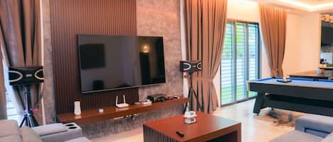 Una sala de estar moderna con televisión de pantalla plana, mesa de billar y asientos cómodos.
