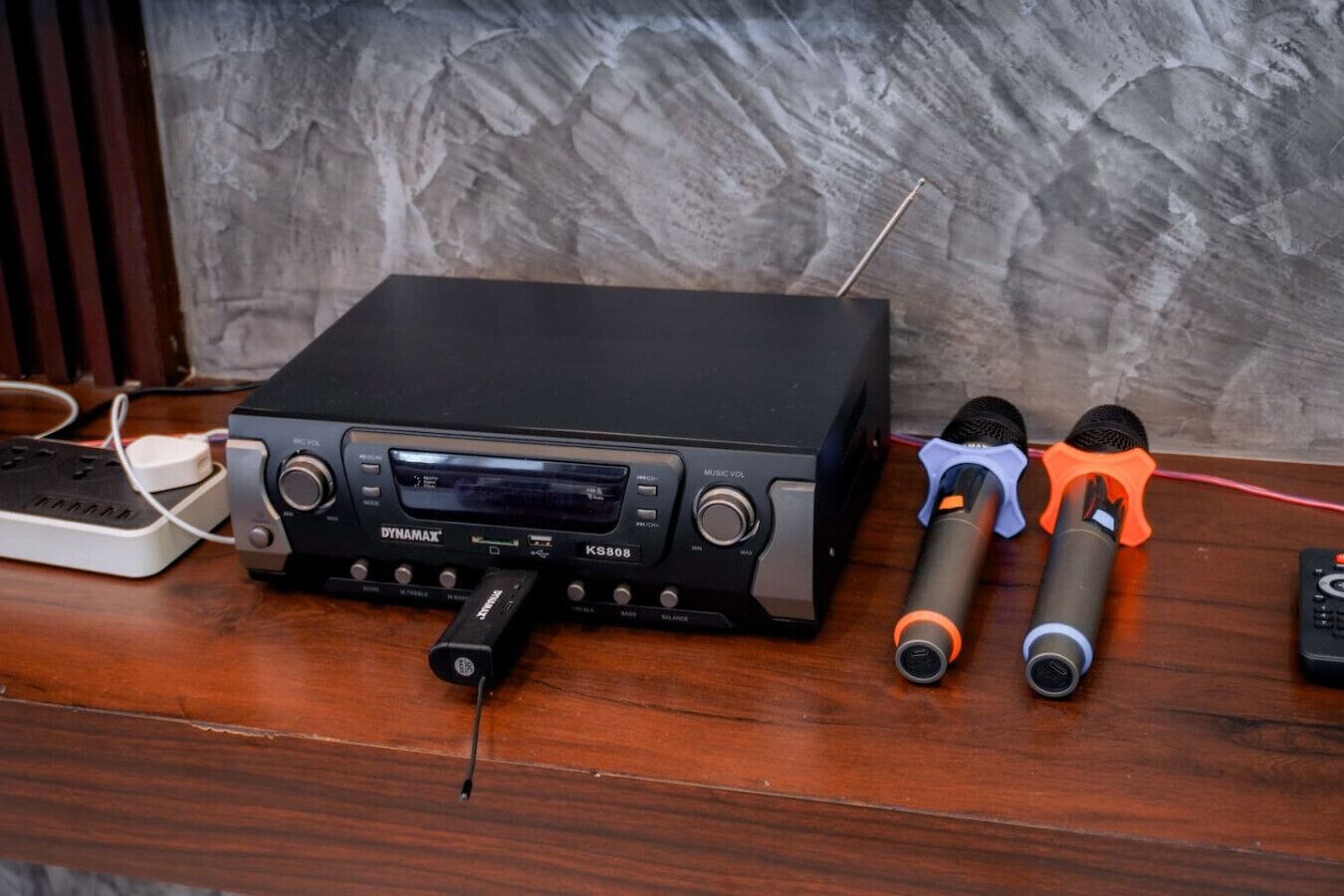 Un mélangeur audio noir doté d’un écran, de deux microphones et d’un câble USB, le tout posé sur une surface en bois.