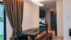 Een moderne eetruimte met een donkerhouten tafel en banken, een raam met gordijnen en een keuken op de achtergrond.