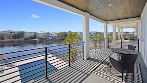 Un espace extérieur abrité comprenant une piscine, une table avec des chaises et une vue sur une rivière et des maisons au loin.