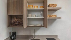 Een moderne keuken met houten kastjes, een inbouwspoelbak en planken met keukengerei.