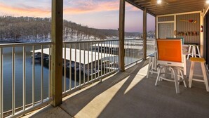 A covered balcony with a view of a snowy landscape and a body of water.