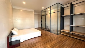 A bedroom with a bed, wooden flooring, a wardrobe with glass doors, and a shelving unit. - MITI House (Ha Tien)