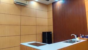 A modern kitchen with a central island, wooden paneling, recessed ceiling lights, and a built-in refrigerator. - MITI House (Ha Tien)