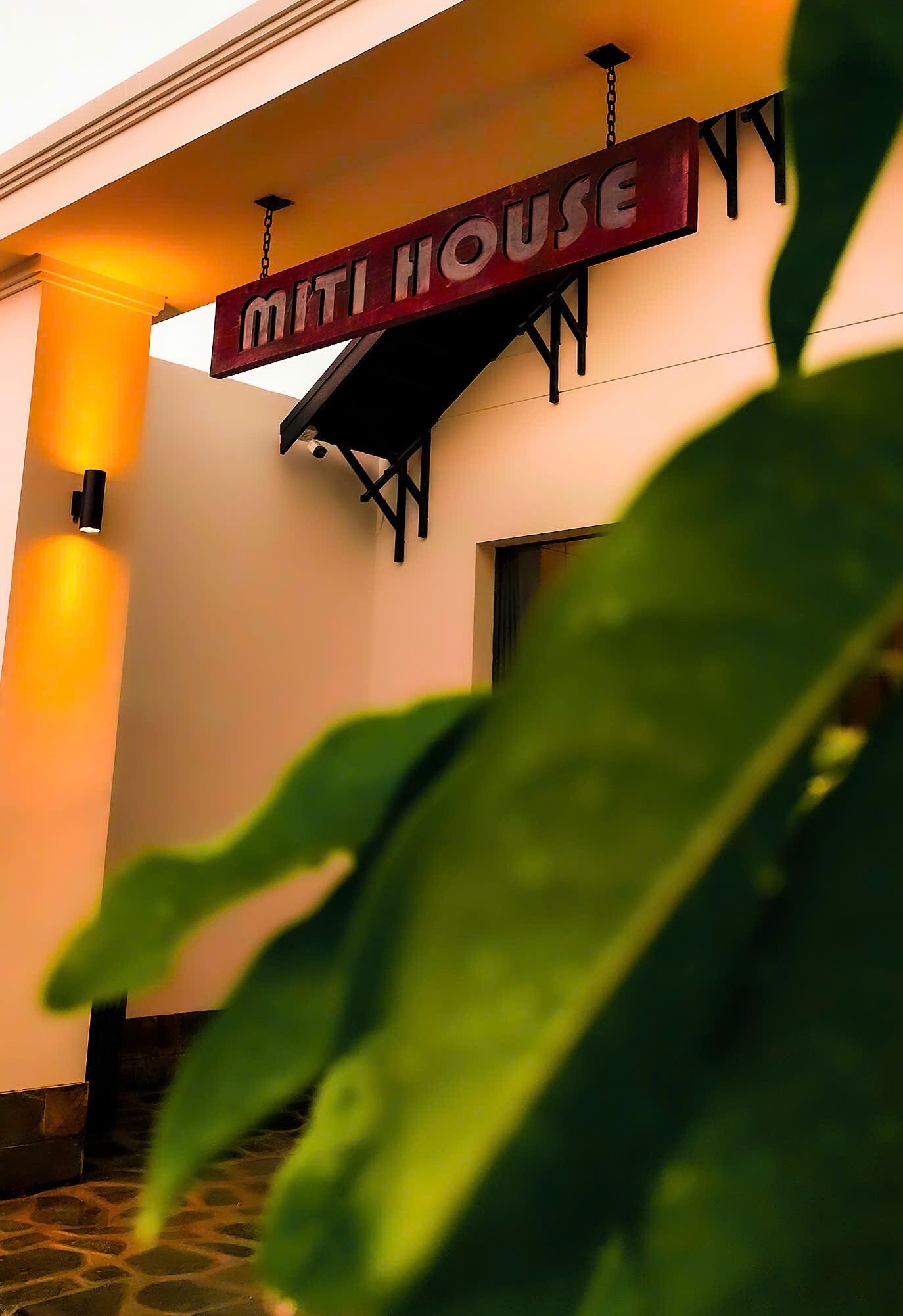 A sign for "MITI HOUSE" with a hanging light fixture above it.