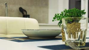 A dining table with a white plate, a glass vase with green plants, and a blue placemat. - Modern & Bright Apartment near Porta Garibaldi (Milano)