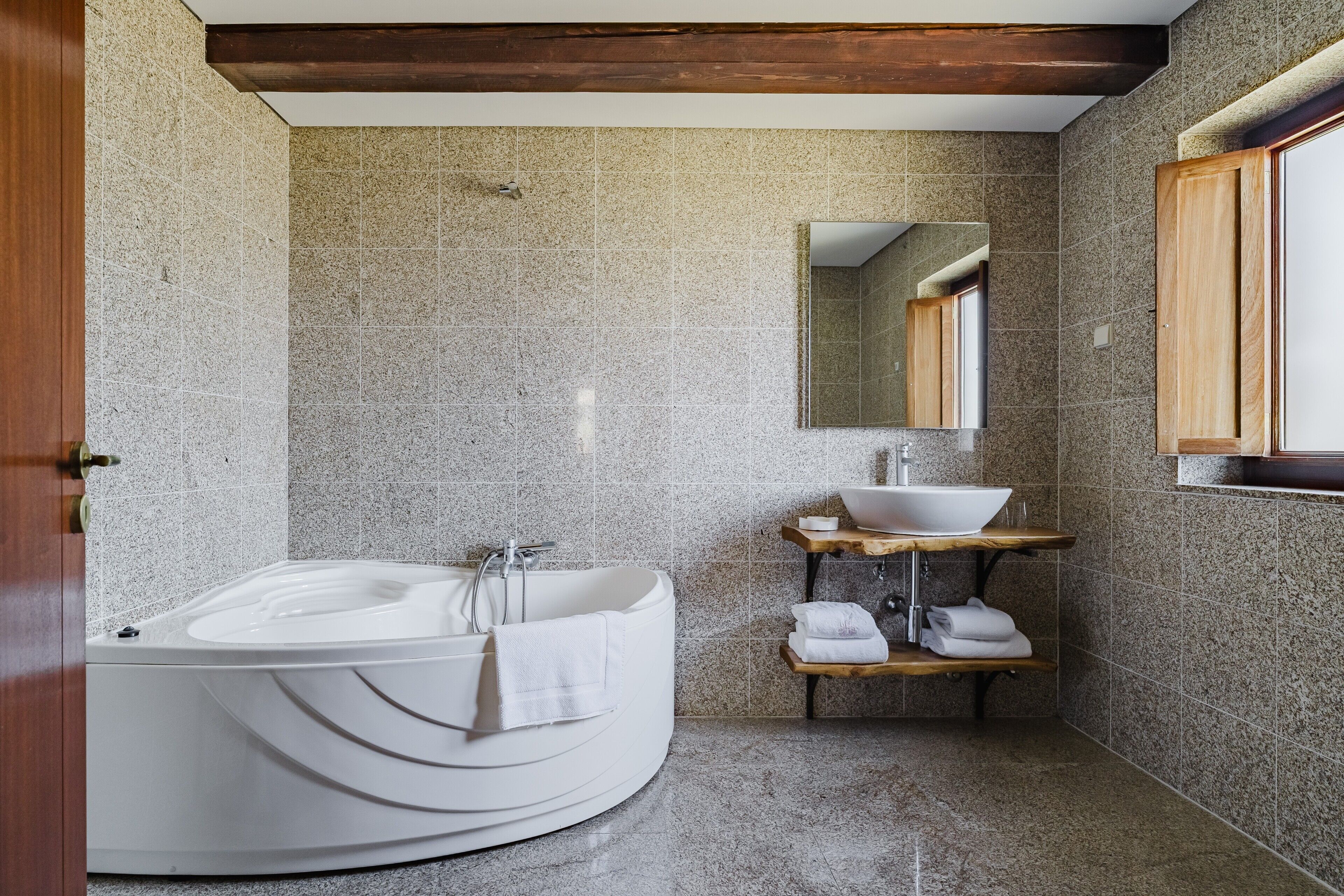 Ein modernes Badezimmer mit freistehender Badewanne, einem Holzlagerraum mit Waschbecken und einem Spiegel darüber.