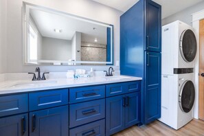 Ein Badezimmer mit einem Waschbecken, einem Spiegel, einem blauen Schrank und einer Waschmaschine.